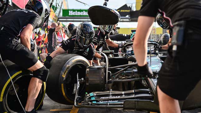 A photo of someone taking an old tire off an F1 car. 