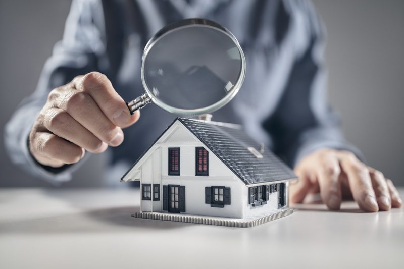 House model with man holding magnifying glass home inspection or searching for a house