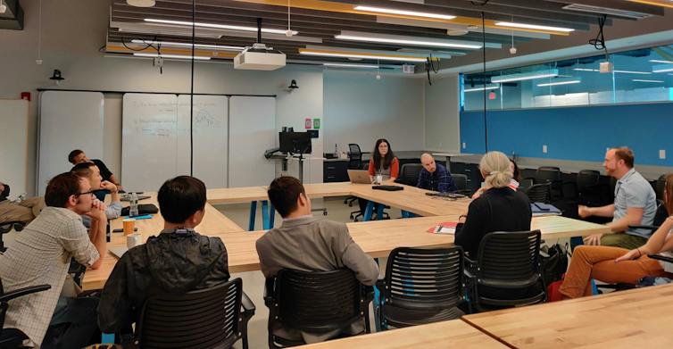 people seated around an open conference table with whiteboards