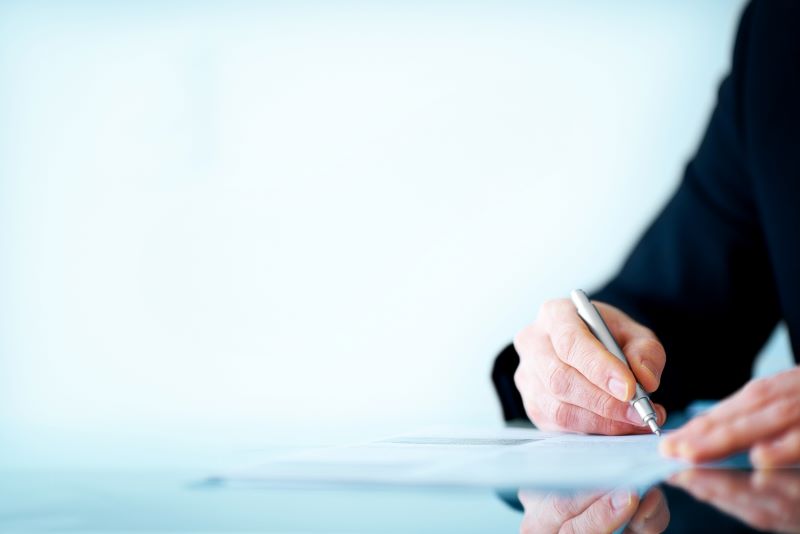 Business benefits professional signing a piece of paper on a clear desk