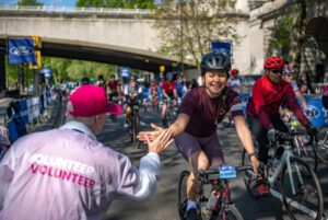 A volunteer interacts with riders as they start the Ford RideLondon-Essex 100 from Victoria Embankment on Sunday 28th May 2023.