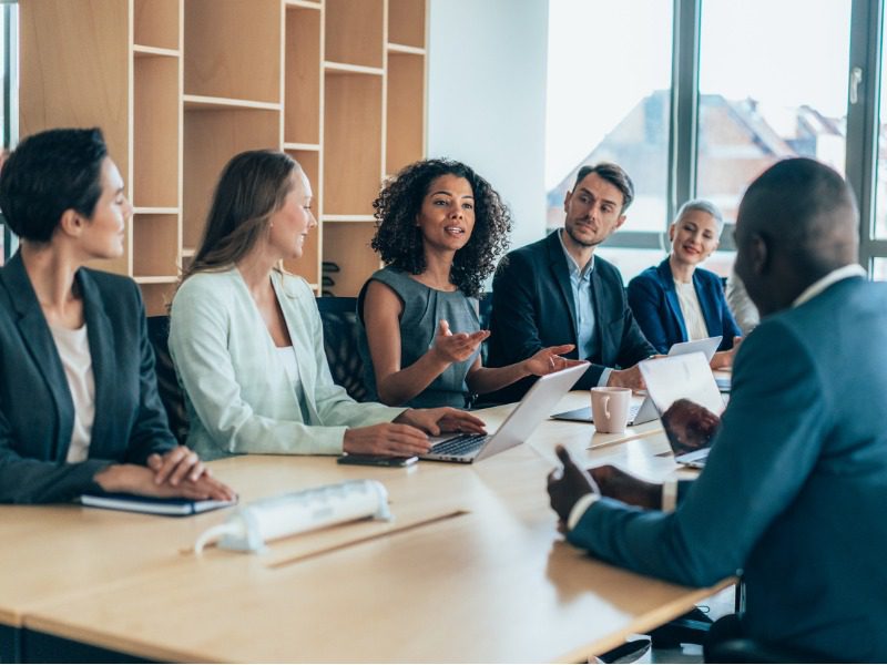 Diverse group of businesspeople sitting together and having a meeting in the brokerage.