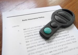 Car keys laying on top of an auto insurance policy