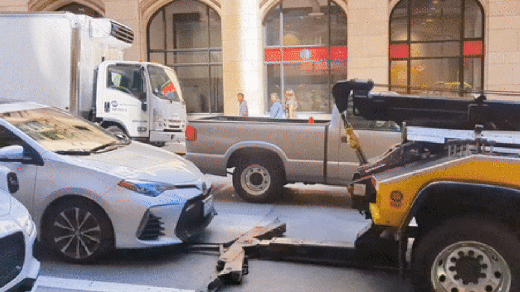 Tow Truck Attempts To Pick Up Occupied Car In The Middle Of Busy Traffic