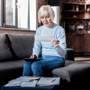 Senior woman looking at papers in shock
