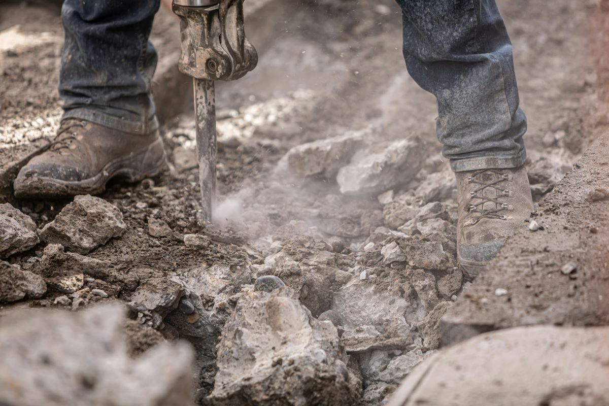 Man using a tool to drill into rocks and dirt