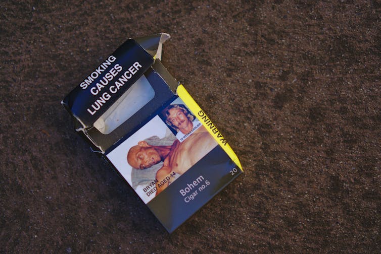 A used cigarette packet on the ground reads
