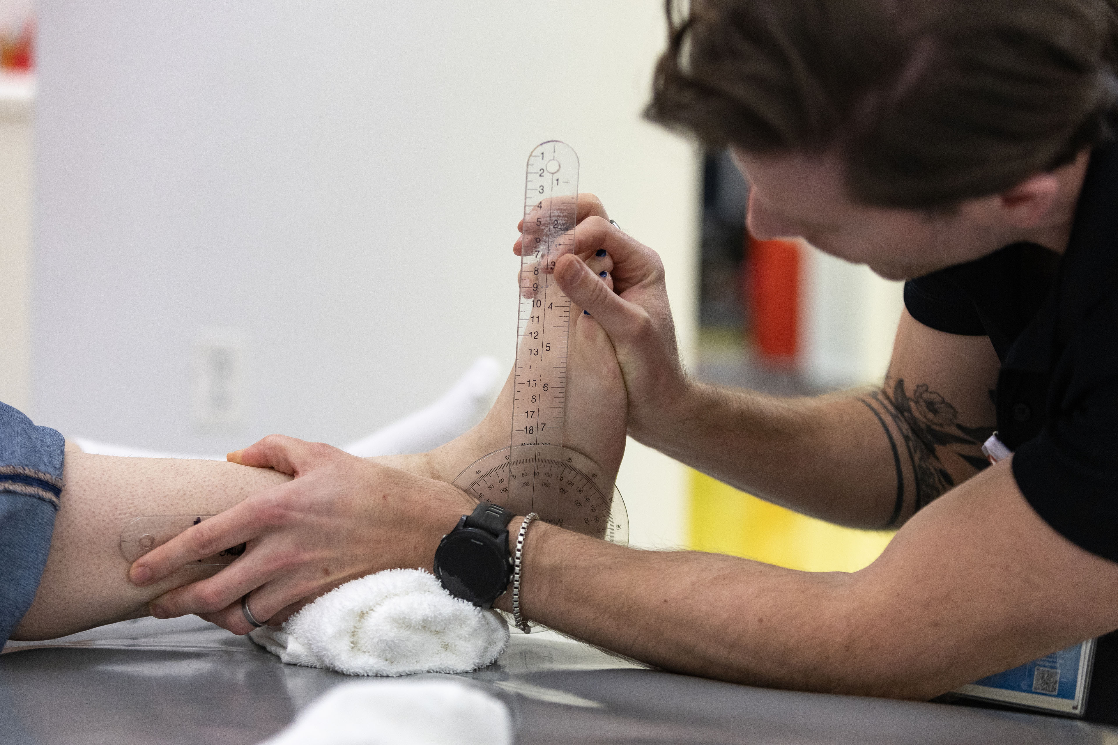 A physical therapist measures the foot of a patient during a therapy session